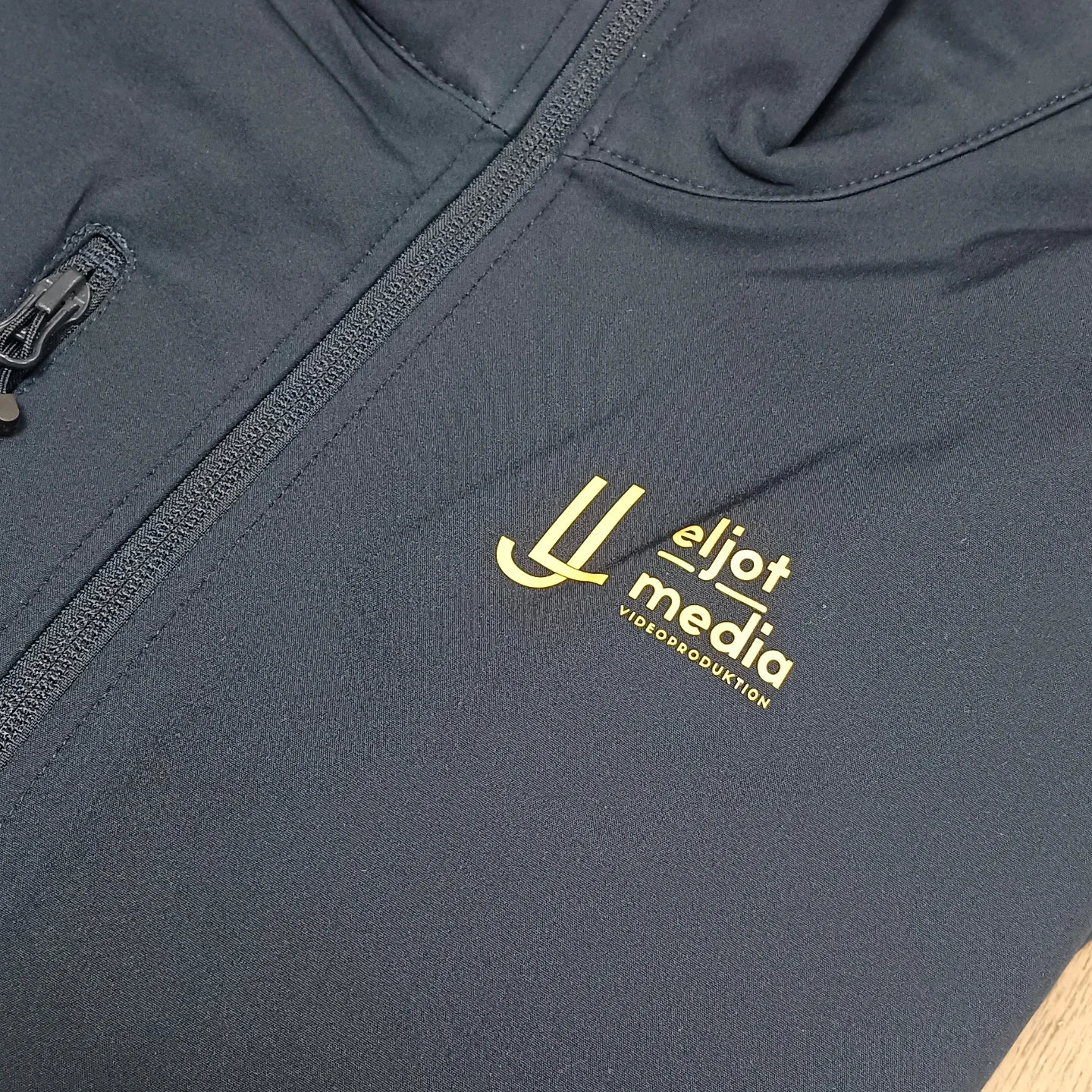 Dunkelblaue Softshelljacke mit gelbem Flexdruck für eljot media